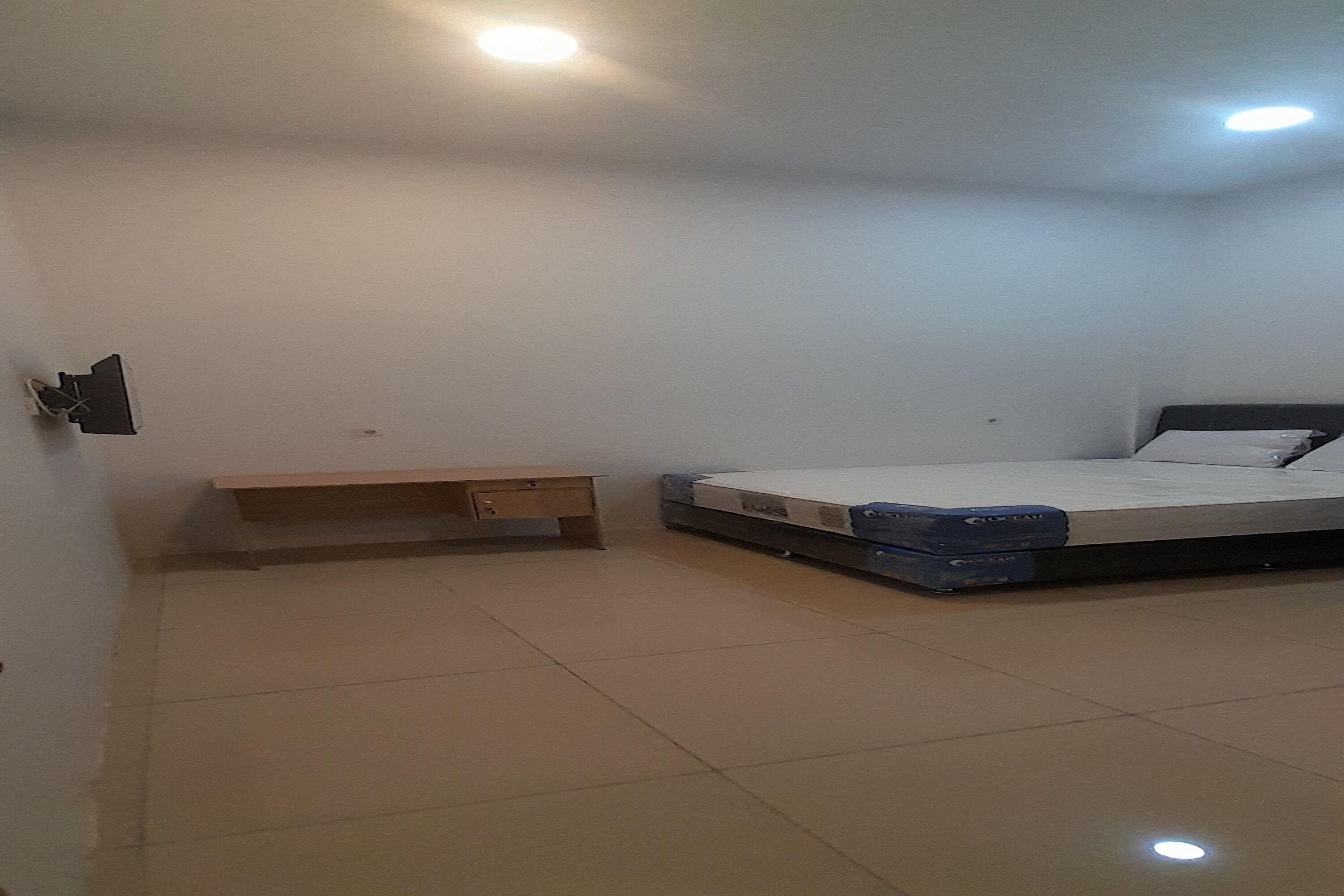 Une chambre à coucher avec un lit, un banc en bois et un luminaire fixé au mur.
