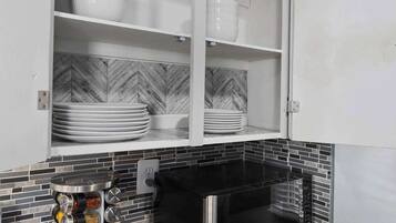 Een keuken met witte kasten, een zwart fornuis en een backsplash van visgraatmozaïek.