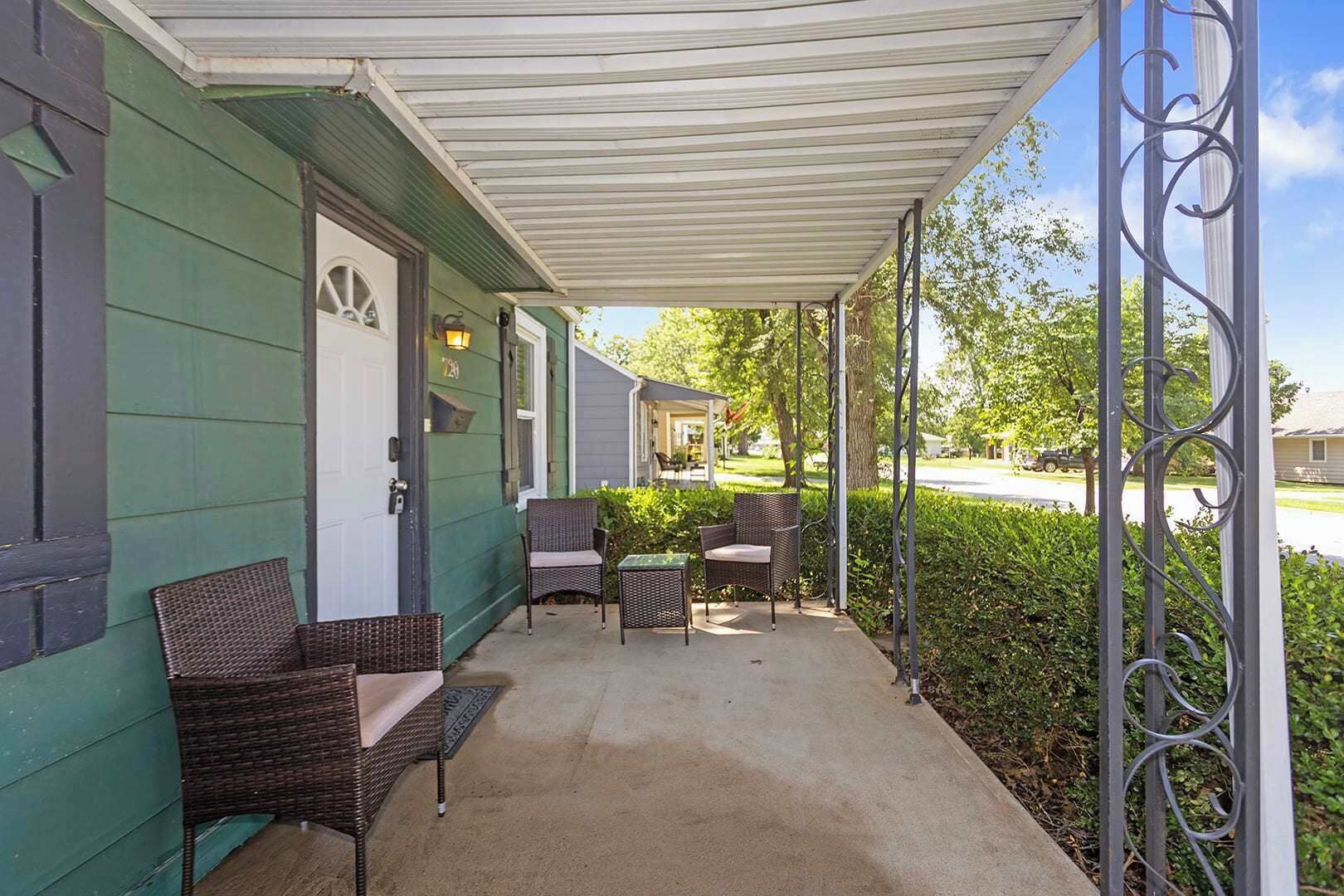 A covered porch with wicker furniture and a metal railing.