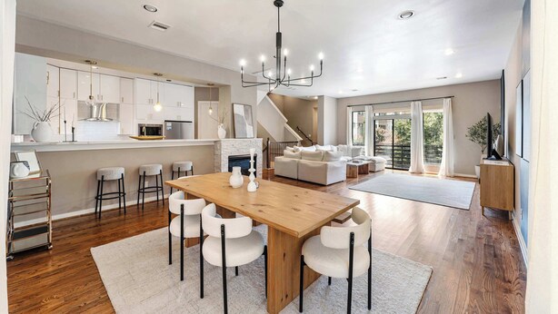 A spacious living area with a wooden dining table, white chairs, and a modern chandelier. - Beautiful Home_Large Space_3 BR_HotTub_Deck (Houston)