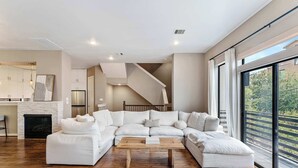 A modern living room with a sectional sofa, a wooden coffee table, and a fireplace. - Beautiful Home_Large Space_3 BR_HotTub_Deck (Houston)