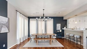 A modern kitchen with a central island, bar stools, and a dining table with benches. - Beautiful Home_Large Space_3 BR_HotTub_Deck (Houston)