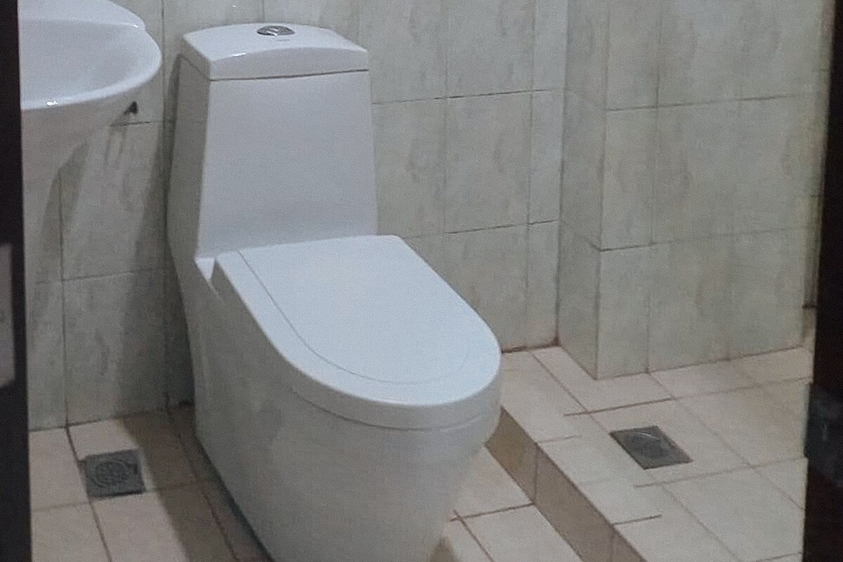 A bathroom with a toilet, sink, and tiled floor.