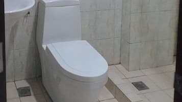 Un baño con inodoro, lavamanos y piso de baldosas.