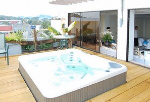 A hot tub on a wooden deck with a glass door leading to a room. - Sky Garden Hotel By Reddoorz (Roxas City)