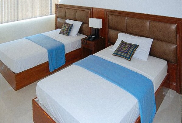 Two single beds with wooden headboards, white linens, and blue throw blankets. - Sky Garden Hotel By Reddoorz (Roxas City)