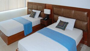 Two single beds with wooden headboards, white linens, and blue throw blankets. - Sky Garden Hotel By Reddoorz (Roxas City)