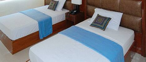 Two single beds with wooden headboards, white linens, and blue throw blankets.