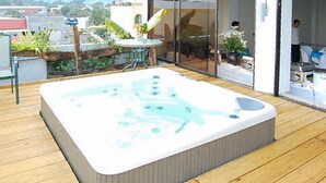 A hot tub on a wooden deck with a glass door leading to a room. - Sky Garden Hotel By Reddoorz (Roxas City)