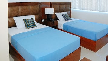 Dos camas individuales con cabeceros de madera, cubrecamas azules y almohadas decorativas.