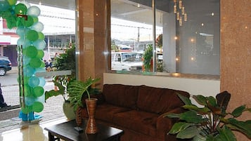 Una habitación con un sofá marrón, una mesita y plantas en macetas.