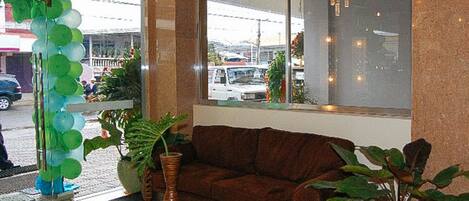 A room with a brown sofa, a small table, and potted plants.