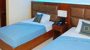 Two adjacent beds with blue bedding, wooden headboards, and bedside lamps.