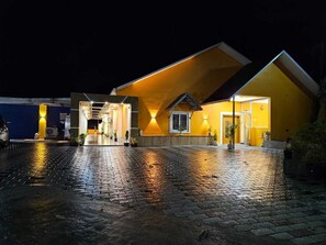 A building with a yellow facade and a paved courtyard. - Coastal Grand Akshaya - Kothagiri (Ootacamund)