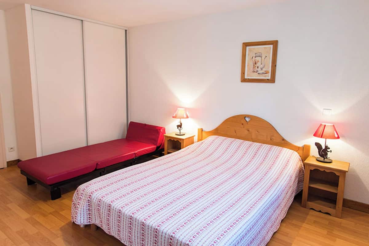 Une chambre avec deux lits, une armoire, un tableau encadré au mur et deux lampes de chevet.