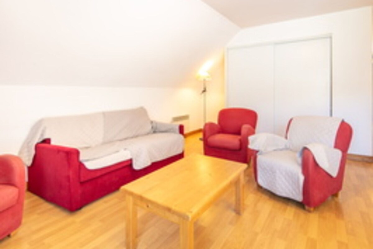 Una habitación con un sofá rojo, una mesa de centro de madera y dos sillones rojos.