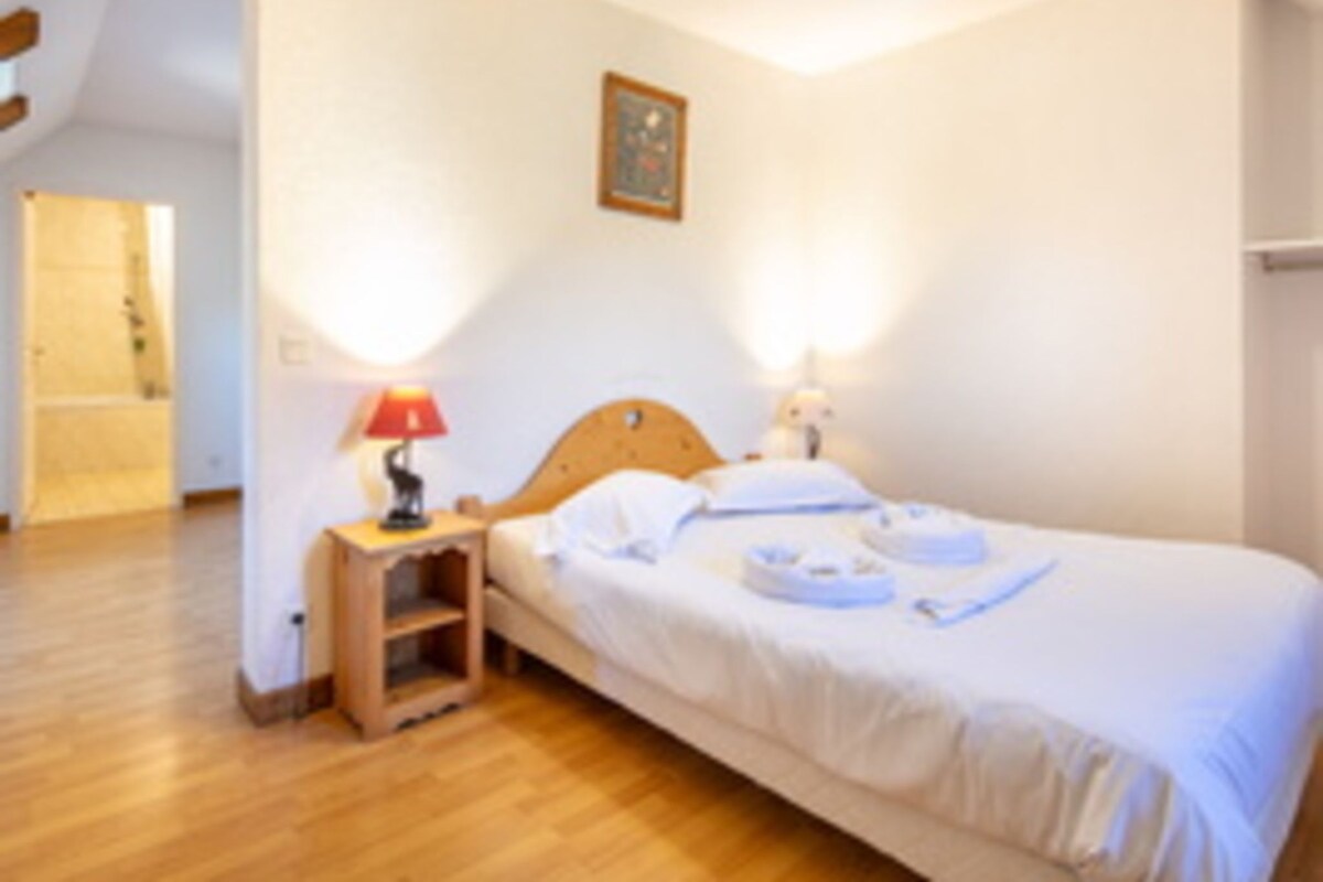 Un dormitorio con cama de madera, mesitas de noche y una puerta que da a otra habitación.