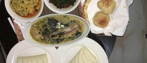 Una mesa con diferentes platos, incluyendo sopa, verduras y dos tipos de pan.
