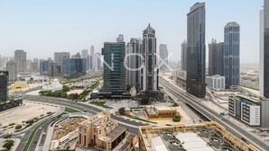 A modern cityscape with high-rise buildings, a mosque, and a busy highway. - 1BR 2510 Forte T2 (Dubai)