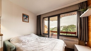 A bedroom with a bed, a window with a view of a mountainous landscape, a radiator, and a small plant on the windowsill. - La Yama - Immodreams - Avoriaz (Avoriaz)