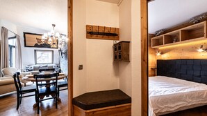 Een gezellige kamer met een bed, een houten bankje, een eethoek met een tafel en stoelen, en een wandplank.