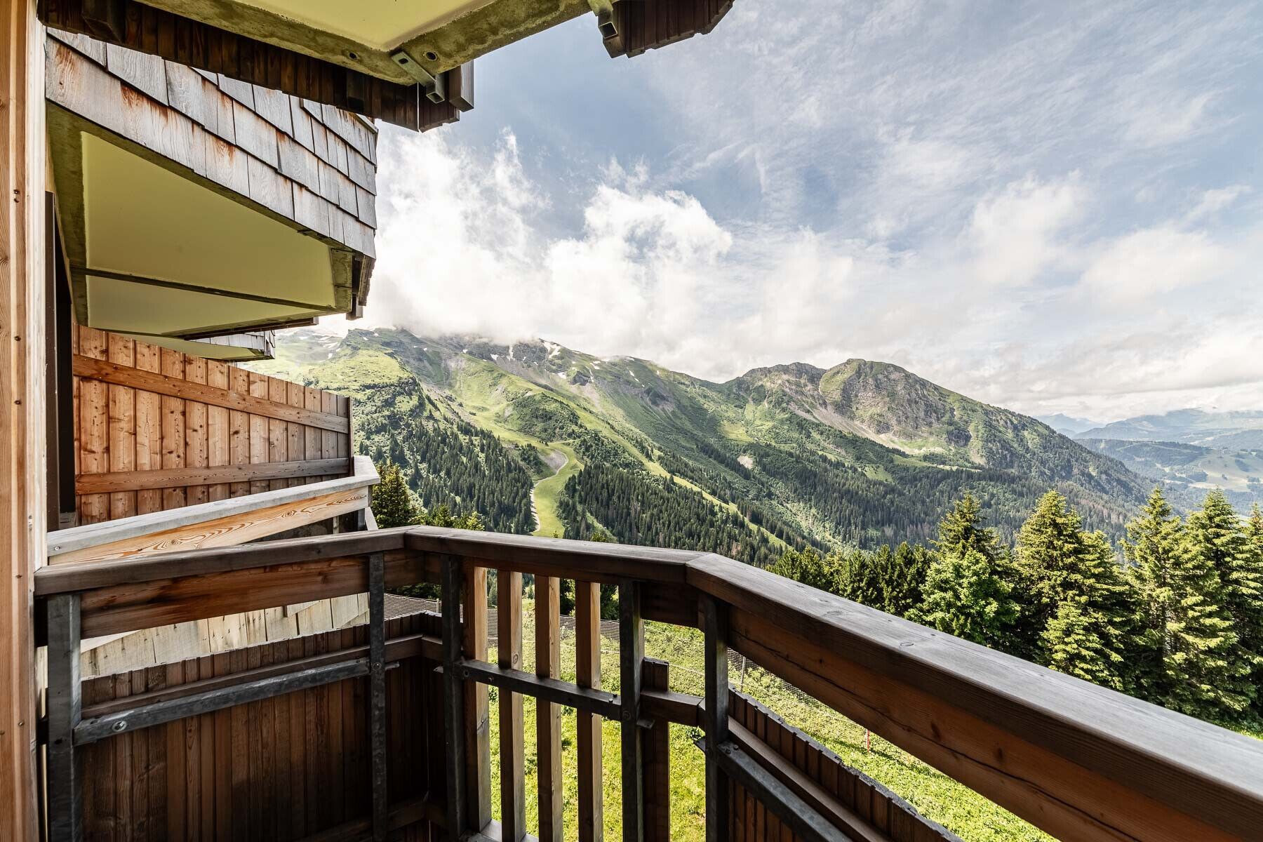 Un balcón de madera con vistas a un paisaje montañoso.
