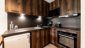 Eine kleine Küche mit Holzausstattung, einer eingebauten Mikrowelle, einer Kaffeemaschine und einem Geschirrspüler.