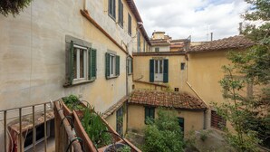 Un patio estrecho con edificios de arquitectura tradicional, incluyendo tejados de teja y contraventanas verdes.