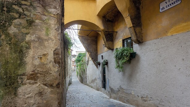 Un estrecho callejón adoquinado con paredes de piedra y un cartel que dice "VIA DEL CANNETO".