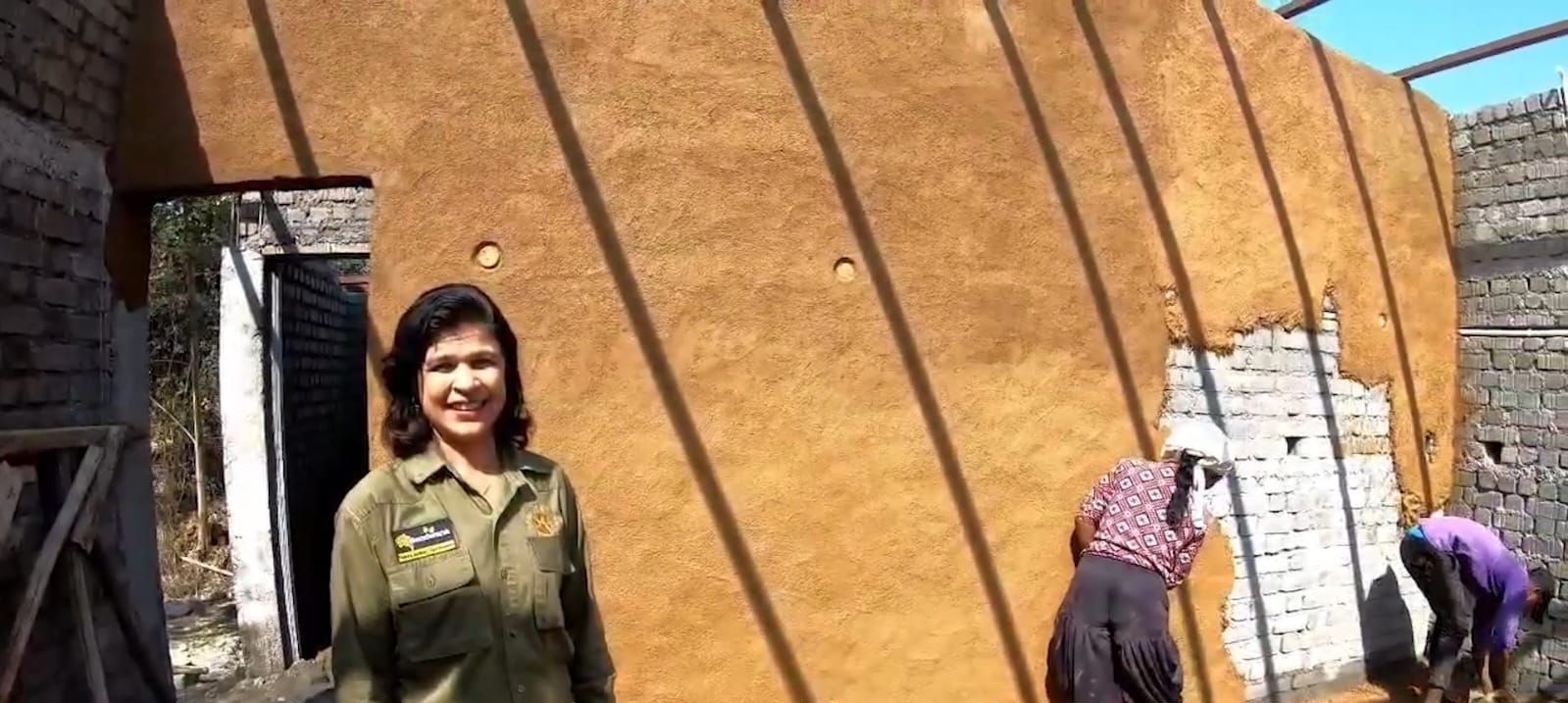 A person in a uniform standing in front of a building under construction.