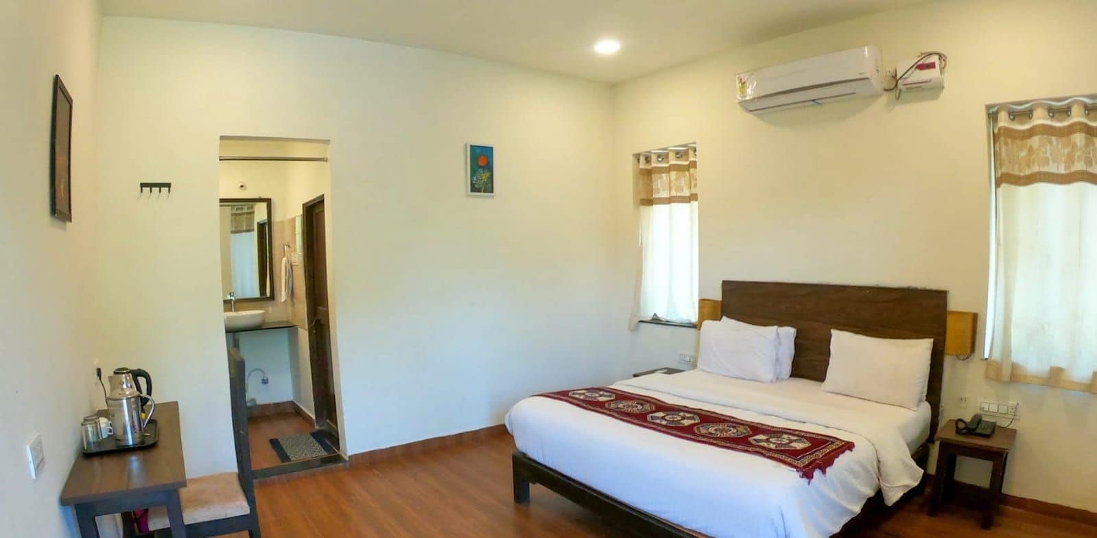 A bedroom with a large bed, a bedside table, a chair, and an air conditioning unit.