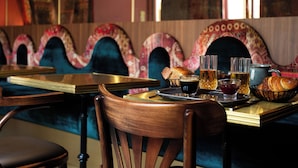 A restaurant with a checkered floor, wooden chairs, a bar area with a tray of food and drinks, and a patterned ceiling. - Hôtel La Particulière (Caen)