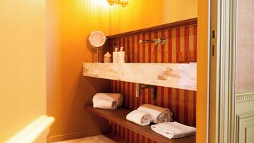 Une salle de bain avec un meuble-lavabo en bois, un miroir et des étagères où sont rangées les serviettes.