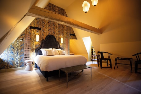 A bedroom with a bed, a bench, and two chairs.. Hôtel La Particulière