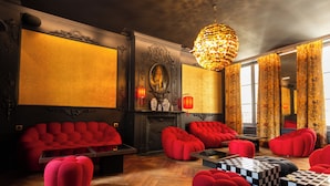 A luxurious room with red upholstered sofas, a chess table, and ornate wall decorations. - Hôtel La Particulière (Caen)