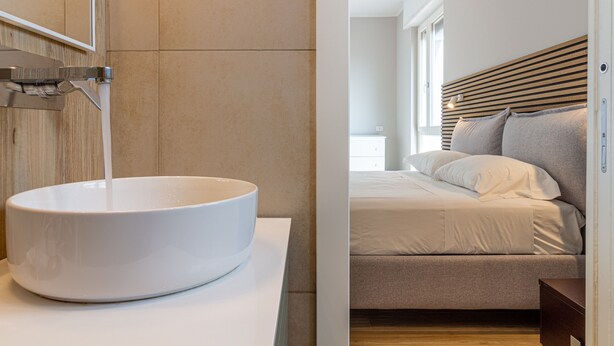 A modern bathroom with a large white vessel sink and a wooden headboard in the adjacent bedroom. - Casa di Ambra - 301 in Monza (Monza)