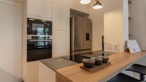 A modern kitchen with stainless steel appliances, a wooden countertop, and hanging pendant lights. - Casa di Ambra - 301 in Monza (Monza)