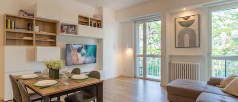 A modern living room with a dining area, a sofa, and a TV.