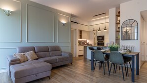 A modern living room with a sectional sofa, a dining area with a table and chairs, and a kitchen in the background. - Casa di Ambra - 301 in Monza (Monza)