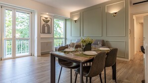 A dining area with a table set for four, large windows, and a radiator. - Casa di Ambra - 301 in Monza (Monza)