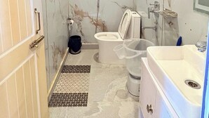 A bathroom with a marble wall, a toilet, a sink, and a shower. - The Grand View Resort (Dehradun)