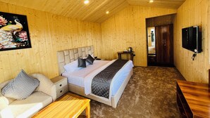 A wooden-paneled room with a bed, a TV, a sofa, and a small table. - The Grand View Resort (Dehradun)
