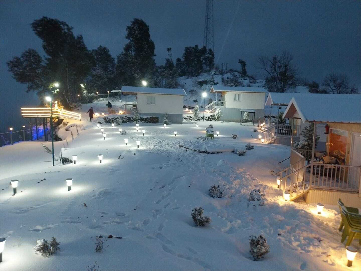 A snow-covered outdoor area with illuminated pathways and buildings, likely a resort or hotel.