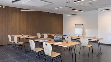 Una sala conferenze con un lungo tavolo, sedie, un portatile e una lavagna.
