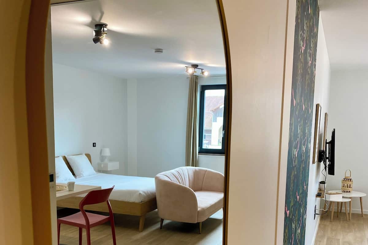 Una habitación de hotel moderna con una cama, una silla, un escritorio y una mesita.