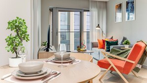 A modern living room with a dining area, a sofa, a coffee table, and a plant. - ShyPen One - Bedroom APT (London)