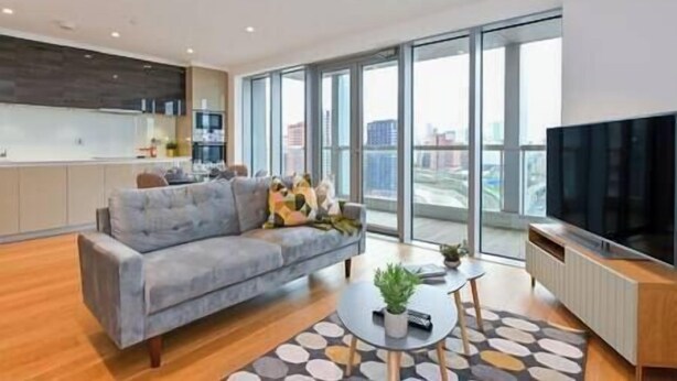Un salon moderne avec un canapé gris, une table basse et un téléviseur.