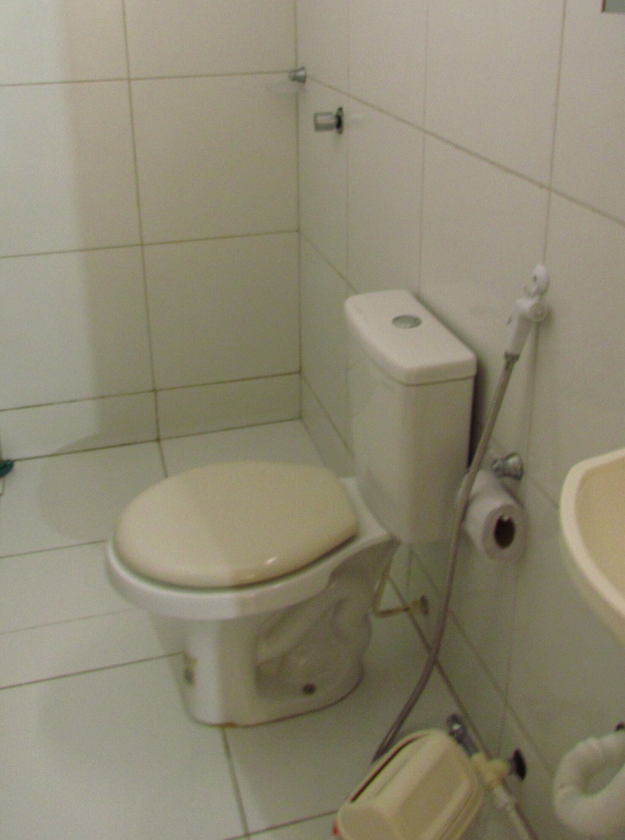 A small, basic bathroom with a toilet, a sink, and a toilet paper holder.