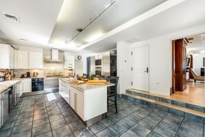 A modern kitchen with a central island, built-in appliances, and a large window providing natural light. - Pease Bay House Cayman Islands (Grand Cayman)