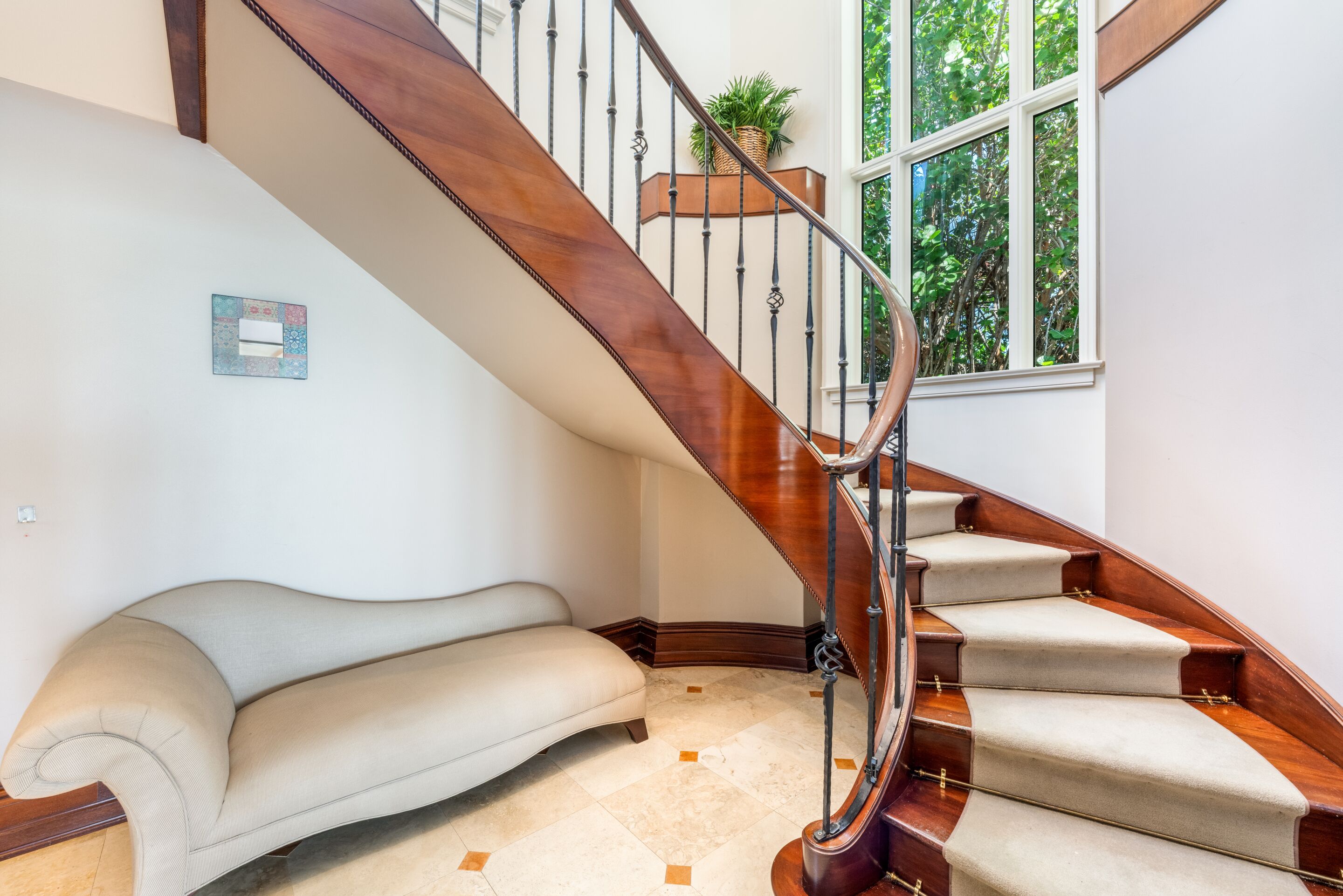 A wooden staircase with a handrail, carpeted steps, and a potted plant on the landing.